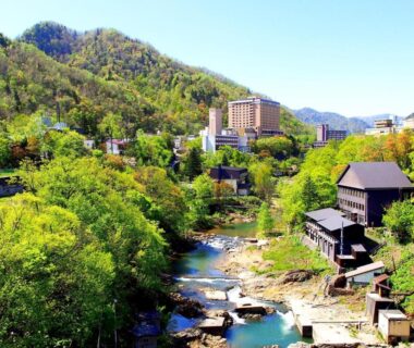 River flowing past wooden ryokan buildings at jyozankei SHIKAnoYU in Hokkaidō, Japan