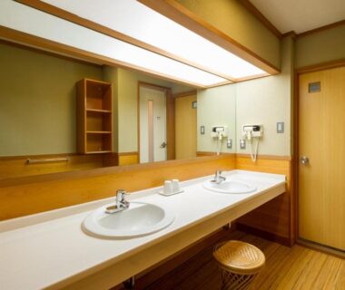 Two sinks with large mirror, wooden stools and wall hairdryers at kinugawaonsen Fukumatsu in Kantō, Tochigi