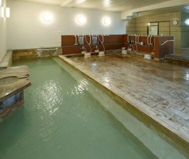 Communal indoor onsen bath with tiled floor and shower stations at mt. inn in Fukushima