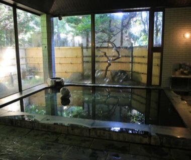 Indoor onsen with stone edging and garden-facing windows at nanaougi ryokan, Kanagawa, Japan
