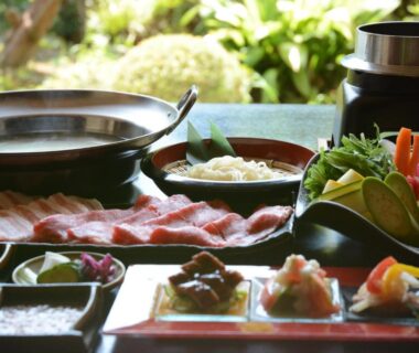 Assorted side dishes and sliced meat with hot pot on table at nanaougi ryokan in Kanagawa