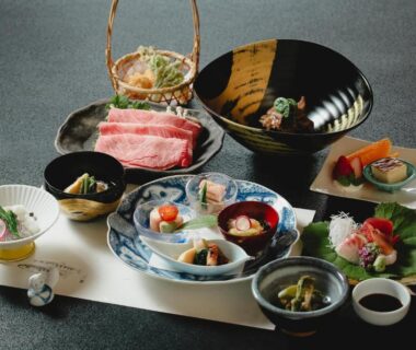 Assorted small dishes with raw fish, thinly sliced meat and ceramic tableware on a placemat