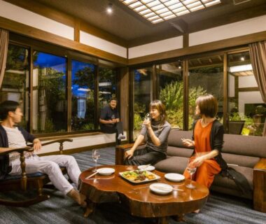 Guests conversing in ryugon lounge around low wooden table with sofas and large windows overlooking a garden