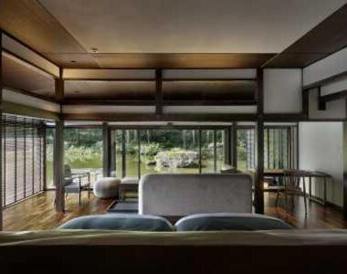 Sofa seating and low table by glass doors opening to garden at Ryugon, Niigata
