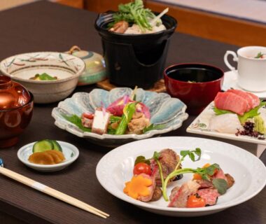 Assorted Japanese multi-course dishes with sashimi, small bowls, soup, and chopsticks on lacquered table at soraichi Miyagi
