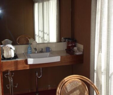 Wooden vanity sink with wicker chair, mirror and sheer curtains in ryokan bathroom at Kintoki Sanso, Hakone