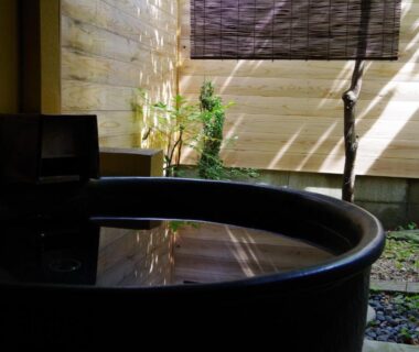 Round wooden soaking tub beside enclosed courtyard garden with bamboo shade at Obama-sō, Toba, Mie