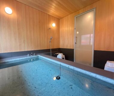 Wood-paneled soaking tub room with shower and stools at Utsuboya-sō Tokyo