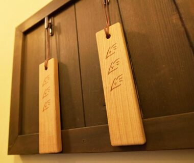 Two carved wooden tags hanging on a dark wooden panel at Ryokan Uribō in Gunma, Kantō