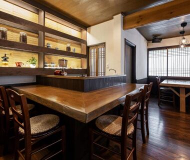 Cozy wooden dining bar with stools, low seating area and shoji screens at Ryokan Uribō in Gunma