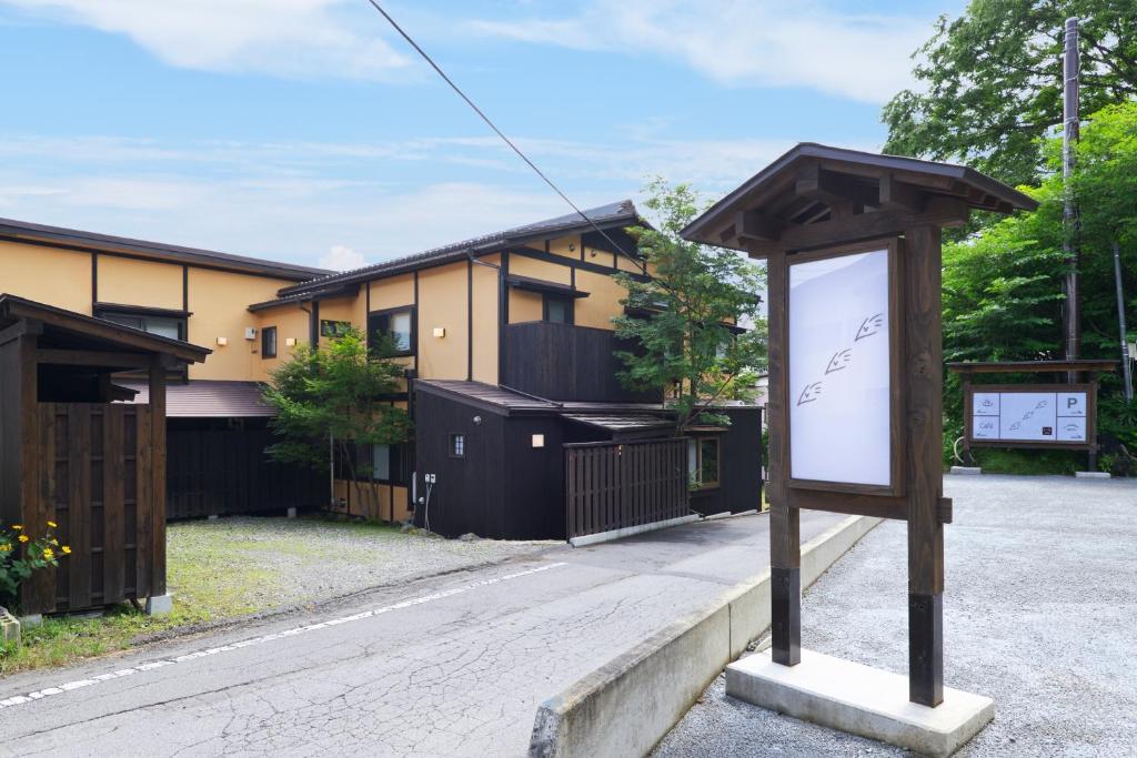 Exterior of Ryokan Uribō in Gunma Wooden sign and two-story ryokan beside a gravel driveway and trees in Gunma, Kantō