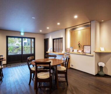 Ryokan dining area with wooden tables, chairs and garden view at Uribō Ryokan Nakamichi, Gunma