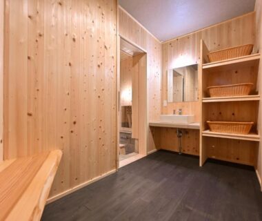 Wood-paneled changing room with bench and washbasin at Uribō Ryokan Nakamichi Urabō in Gunma Kantō