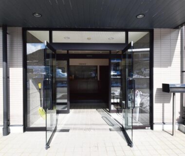 Glass double doors leading into ryokan foyer with tiled walkway and covered canopy at Oyado Kokoro in Gifu