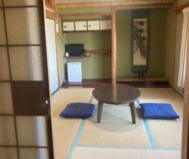 Traditional tatami room with low round table, zabuton cushions, shoji screens and wall scroll at Oyado et table Momo Wakayama