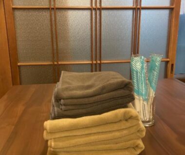 Stacked towels and toothbrushes on wooden table with shoji screen at Oyado et table Momo, Wakayama