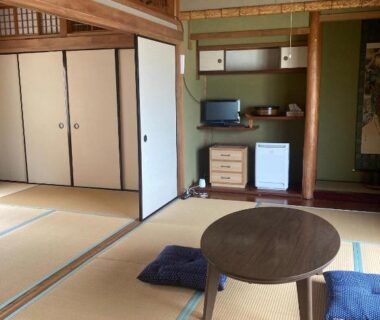 Traditional tatami room with low round table, zabuton cushions, sliding fusuma doors and alcove at Oyado et table Momo Wakayama