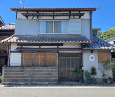 Two-story traditional frontage with tiled roof, bamboo blinds and potted plants at Oyado et table Momo in Wakayama