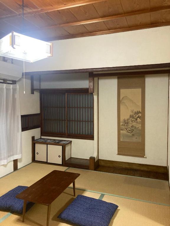 Tatami Room Oyado et table Momo Wakayama Tatami room with low wooden table, blue zabuton cushions and tokonoma with hanging scroll at Oyado et table Momo, Wakayama
