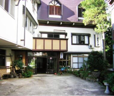 Courtyard and traditional entrance at Oyado Marutoya in Nagano with potted plants and multi-story facade