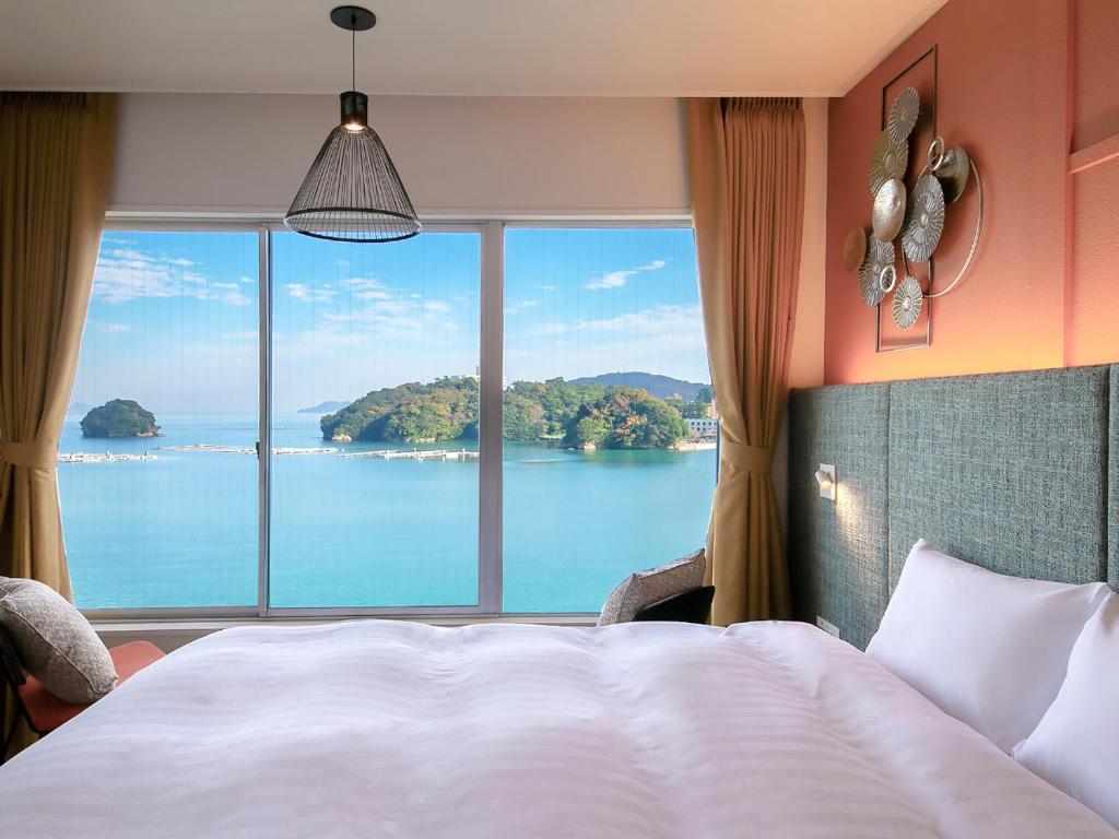 Sea View Guestroom Oyado Andon Toba Mie Bed by floor-to-ceiling window overlooking sea and islands at Oyado Andon Toba, Mie, Kansai