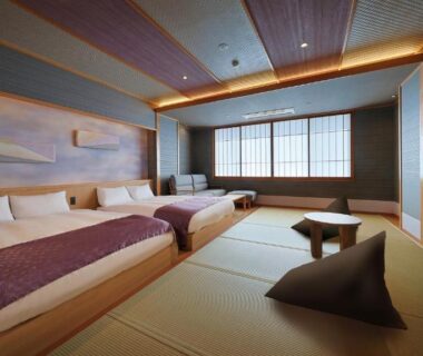 Tatami-floored guest room with two beds, low table and shoji windows at Ryokan Sanjirō in Miyagi, Tōhoku