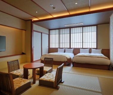 Spacious tatami room with two beds, low table and shoji screens at Ryokan Sanjirō in Miyagi