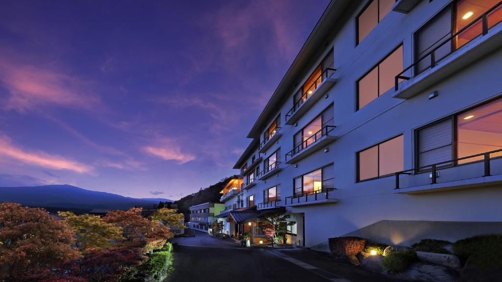 Twilight exterior view Ryokan Sanjirō Miyagi Tōhoku Japan Dusk exterior of multi-story ryokan with illuminated windows and mountain backdrop in Miyagi Tōhoku