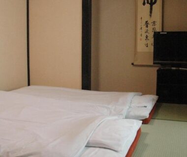 Japanese tatami room with futon bedding, sliding screens and wall scroll at Kiyoshigekan in Gunma