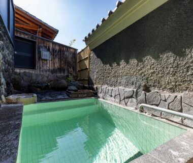 Tiled outdoor onsen bath beside stone wall at Kiyoshigekan in Gunma