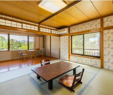 Traditional tatami room with low table, floor cushions, shoji screens and garden-facing windows at Kiyoshigekan in Gunma