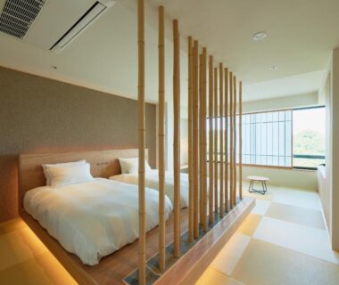 Raised tatami bedroom with twin beds and wooden slatted divider at Kuroshio Sō in Wakayama