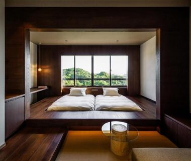 Raised tatami sleeping area with futons, wooden interior and large window overlooking greenery at Kuroshio Sō, Wakayama
