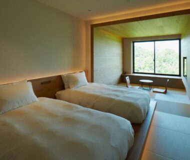 Serene guest room with twin beds, tatami flooring and large window overlooking greenery at Kuroshio Sō, Wakayama