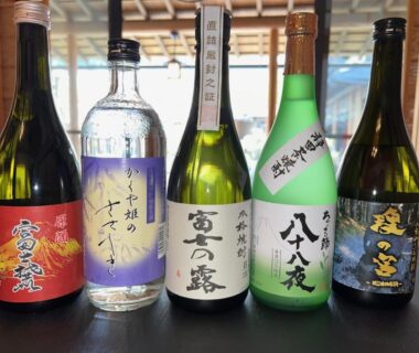 Five assorted sake bottles on a wooden counter at Suikōen Sakura in Shizuoka, Chūbu, Japan