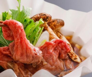 Thinly sliced beef and mushrooms simmering in a paper hot pot with greens and chopsticks at Miharu-en Nara