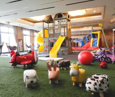 Indoor children's play area with slides, climbing structure, turf floor and animal ride-ons at Miharu-en in Nara