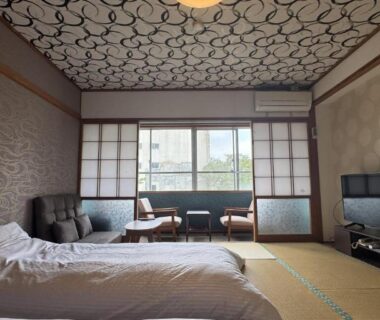 Tatami-floored room with futon bedding, shoji screens, low seating area and window overlooking greenery