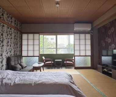 Tatami room with two beds, shoji screens, low table and window overlooking garden at Ryokan Tsuruya in Nagano