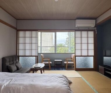 Tatami floored guest room with twin beds, shoji screens, low seating and TV at Ryokan Tsuruya, Nagano