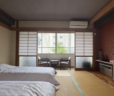 Traditional tatami room with twin beds, shoji screens and low table by the window at Ryokan Tsuruya Nagano