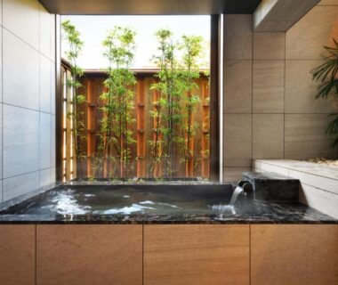 Stone-lined indoor onsen with bamboo screen and flowing spout at Tsurukō in Ishikawa, Chūbu, Japan