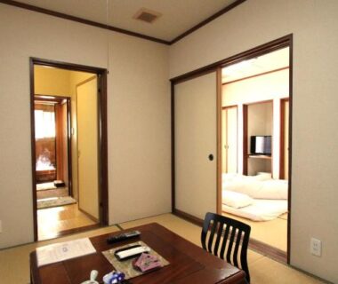 Traditional tatami room with low table, tea set, sliding doors and futon area at the ryokan in Gifu