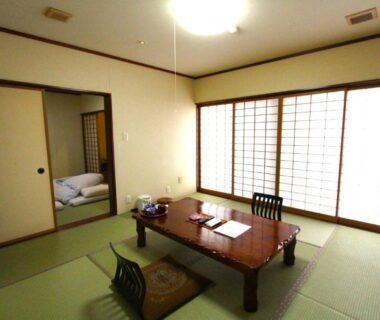 Tatami room with low wooden table, zabuton cushions and futon in adjacent space at Hirayunomori Bettei Yuuka Sanzōan, Gifu