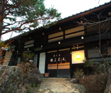 Traditional wooden entrance of Hirayunomori Bettei Yuuka Sanzōan with stone path and pine tree in Gifu