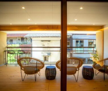Wooden balcony with rattan chairs and low stools overlooking neighborhood at MACHIYADO ICHIRYU, Gifu