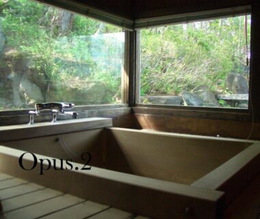 Indoor wooden soaking tub with large windows overlooking a rock garden at Yasuragi no Bettei Shikitei Yamanashi
