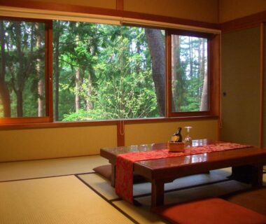 Traditional tatami room with low table and window overlooking forest at Yasuragi no Bettei Shikitei, Yamanashi
