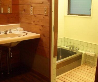 Small indoor tiled bath with wooden paneling and sink at Yasuragi no Bettei Shikitei, Yamanashi Chūbu