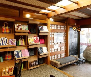Wooden ryokan entrance with shōji doors, bench and shelves of colorful items at Yanagi-sō in Hyōgo, Kansai